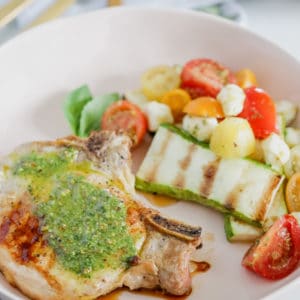 Pesto Grilled Pork Chops! Juicy grilled pork chops topped with a fresh and flavorful pesto sauce are ready to enjoy in under 30 minutes; this dinner tastes like the perfect summer meal!