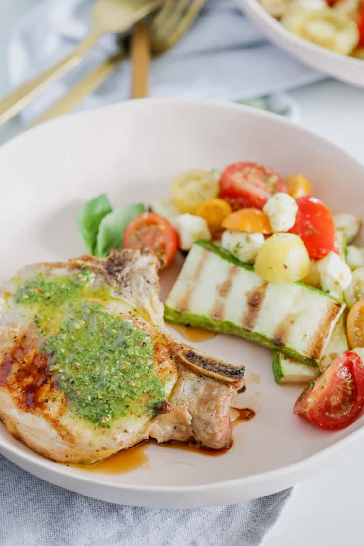 Pesto Grilled Pork Chops! Juicy grilled pork chops topped with a fresh and flavorful pesto sauce are ready to enjoy in under 30 minutes; this dinner tastes like the perfect summer meal!