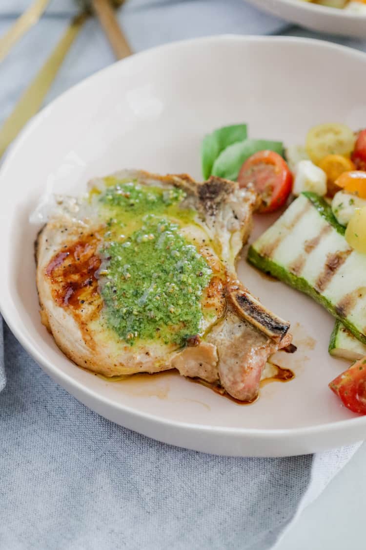 Pesto Grilled Pork Chops! Juicy grilled pork chops topped with a fresh and flavorful pesto sauce are ready to enjoy in under 30 minutes; this dinner tastes like the perfect summer meal!