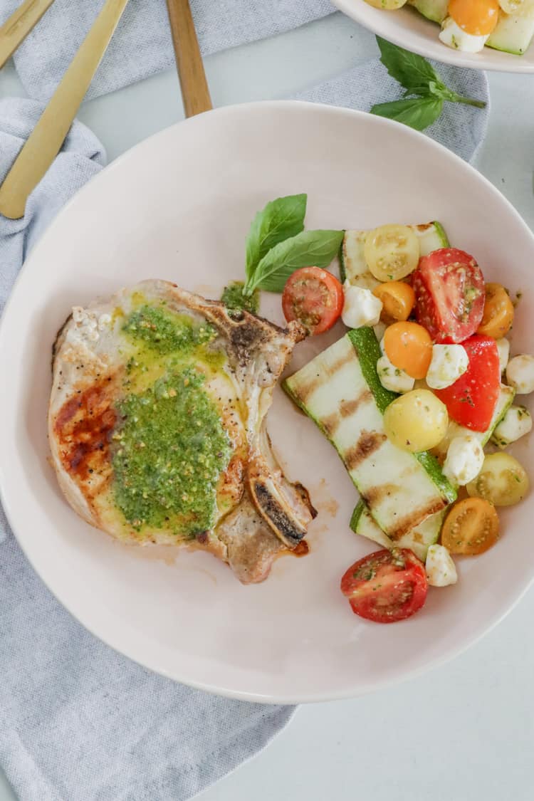 Pesto Grilled Pork Chops! Juicy grilled pork chops topped with a fresh and flavorful pesto sauce are ready to enjoy in under 30 minutes; this dinner tastes like the perfect summer meal!