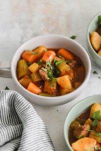 Beef Stew with carrots, potatoes and celery in a white bowl