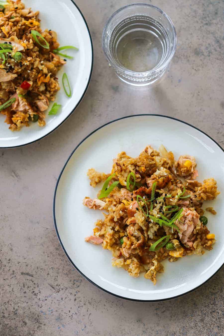 Fried rice and cauliflower with flaked salmon on a white plate