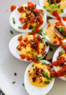 sriracha deviled eggs with bacon on a white plate