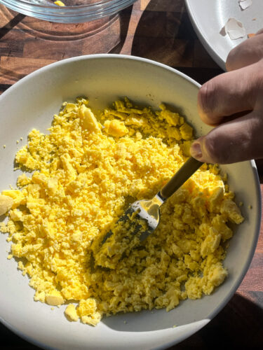 bowl of egg yolks, mashed with a fork to prepare deviled egg filling