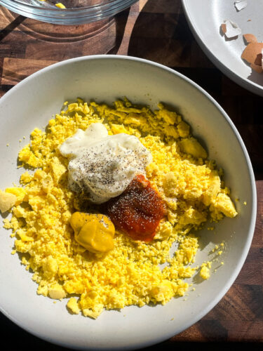 egg yolks, mayo, mustard, sriracha and spices in a bowl for deviled egg mixture