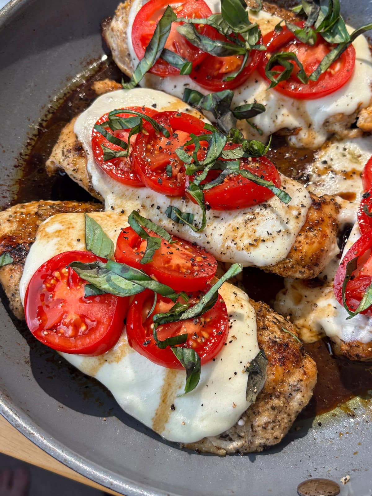 A pan with chicken, mozzarella tomatoes and basil.
