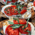 A pan with chicken, tomatoes and mozzarella cheese on it.