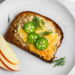 A plate with a slice of bread and some apples.