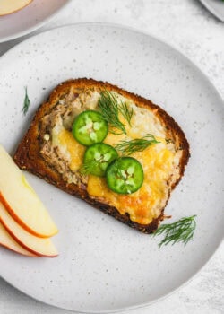A plate with a slice of bread and some apples.
