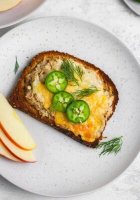 A plate with a slice of bread and some apples.