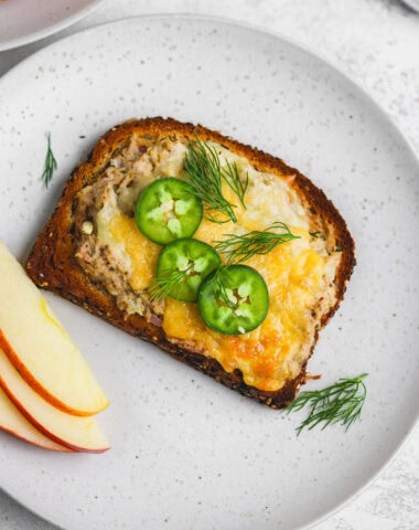 A plate with a slice of bread and some apples.