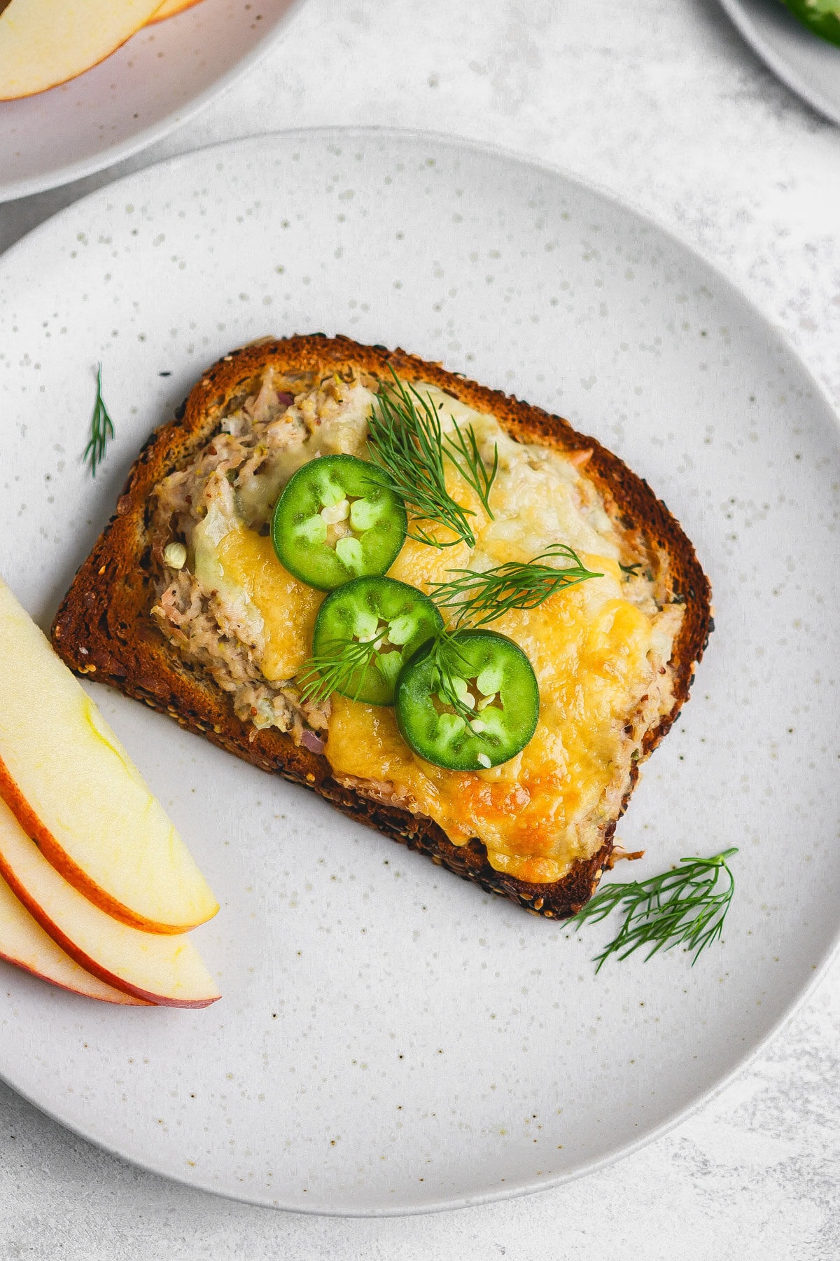 A plate with a slice of bread and some apples.